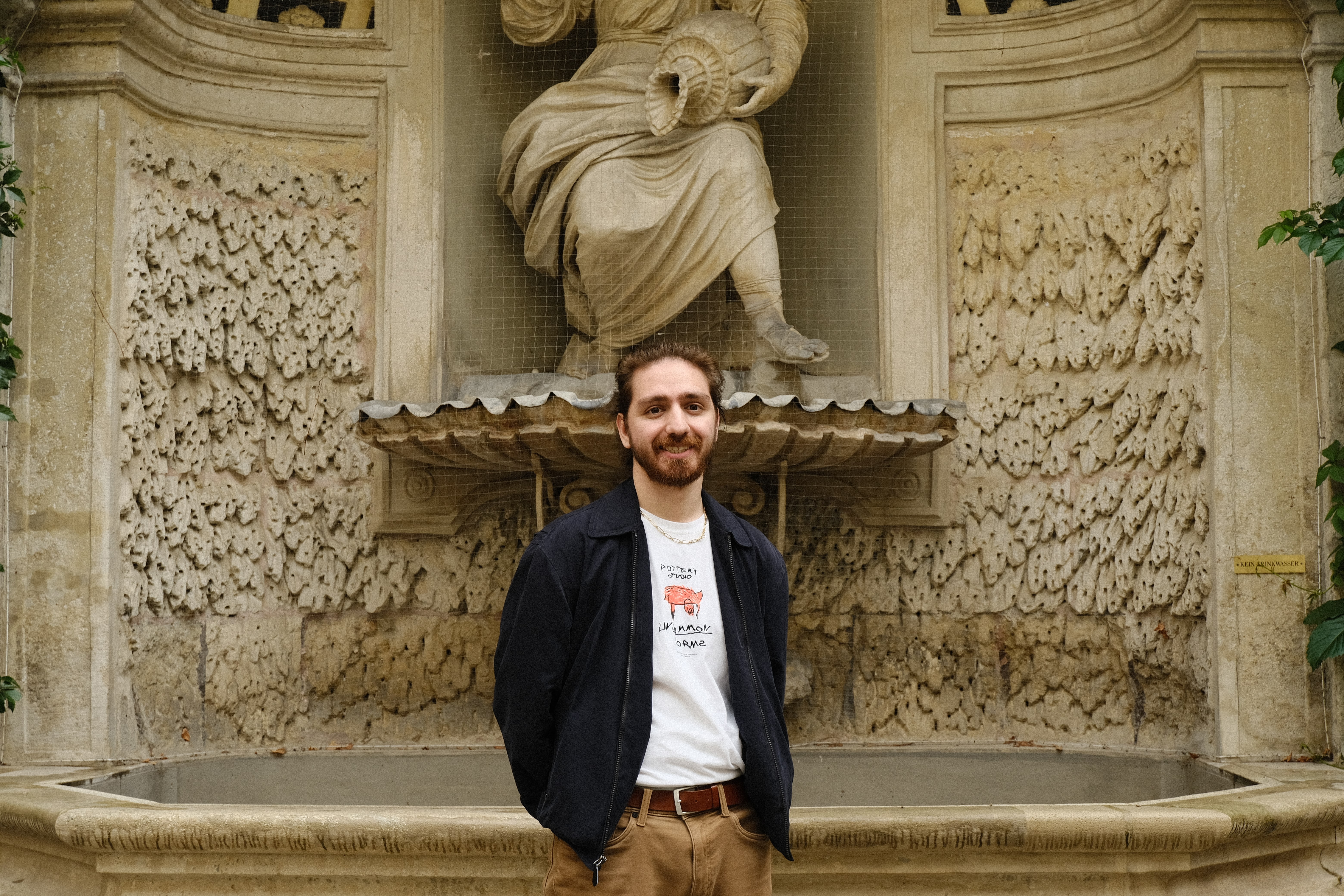 Photo of Mustafa Bolat posing in front of an old marble fountain